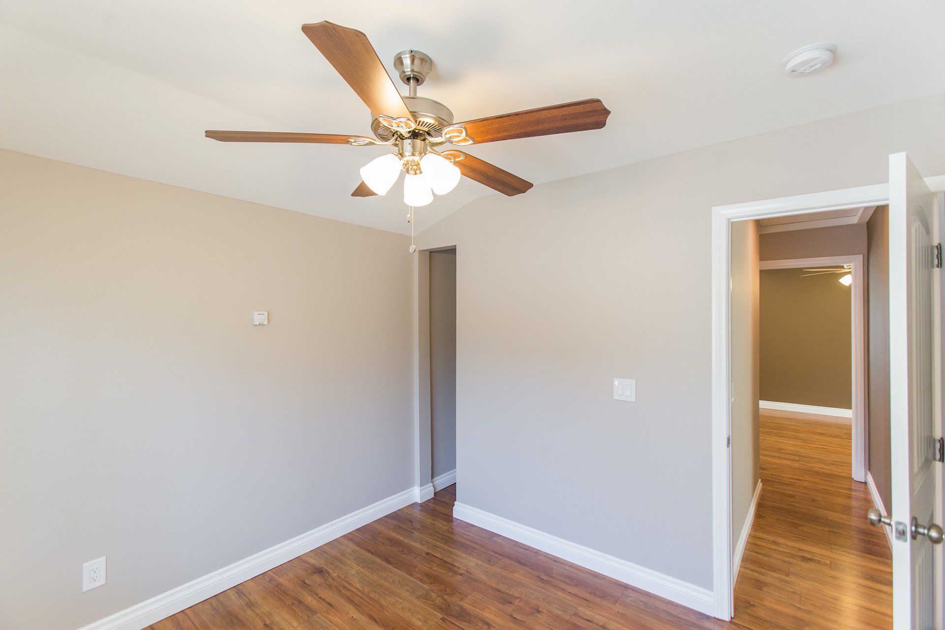 An empty room with a ceiling fan and a door
