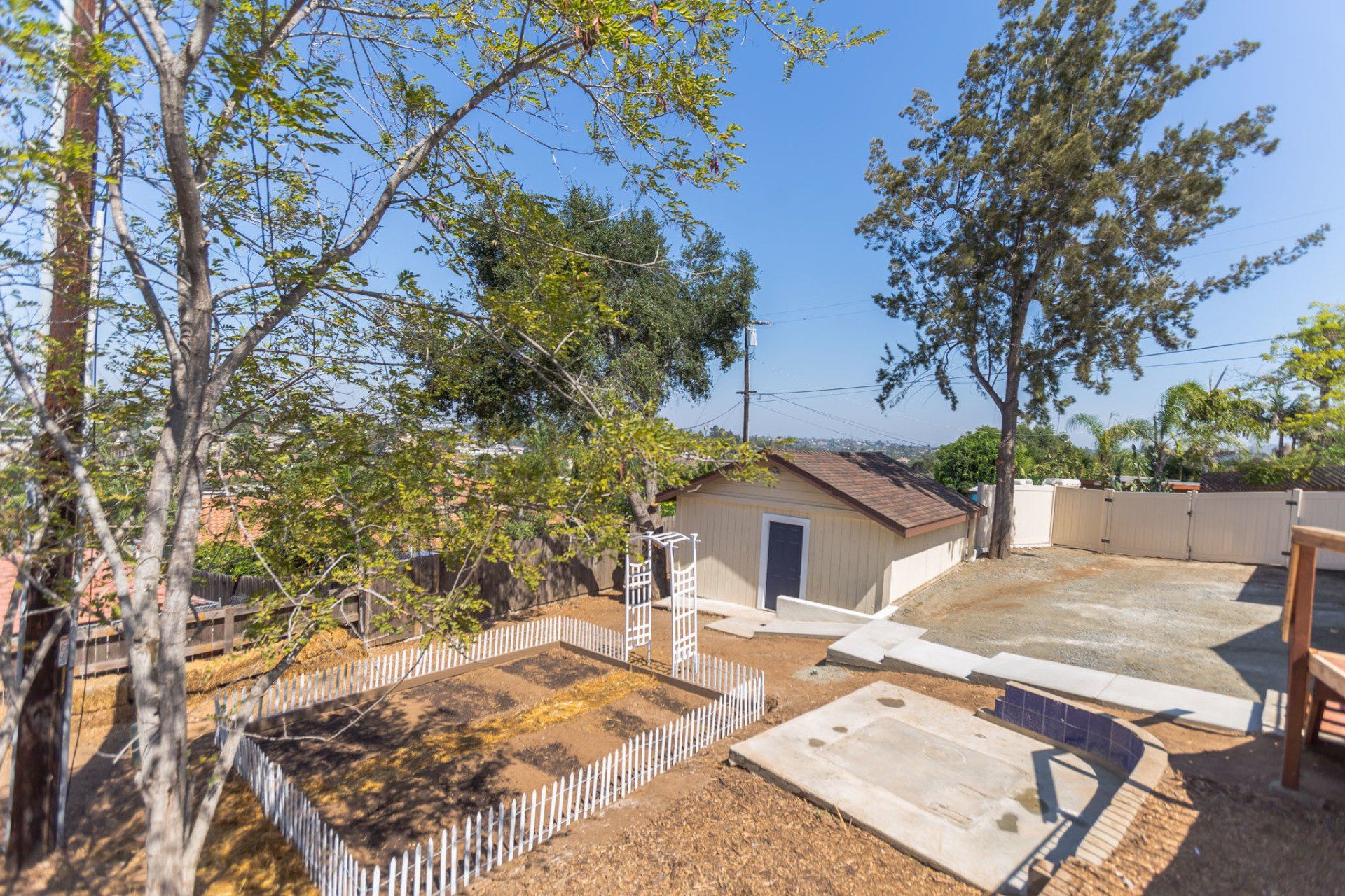 A backyard with a white fence and trees