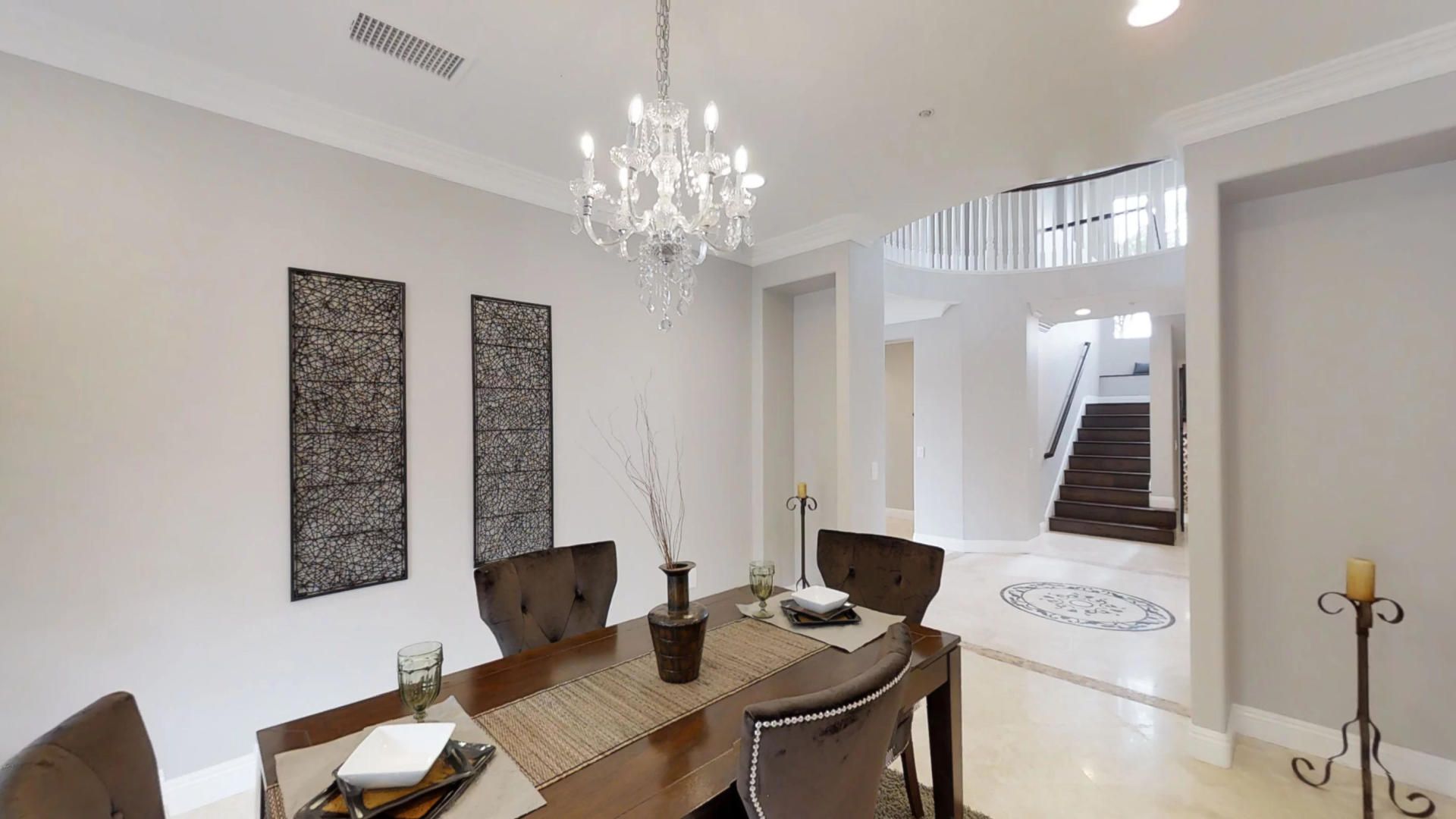 A dining room with a table and chairs and a chandelier hanging from the ceiling.