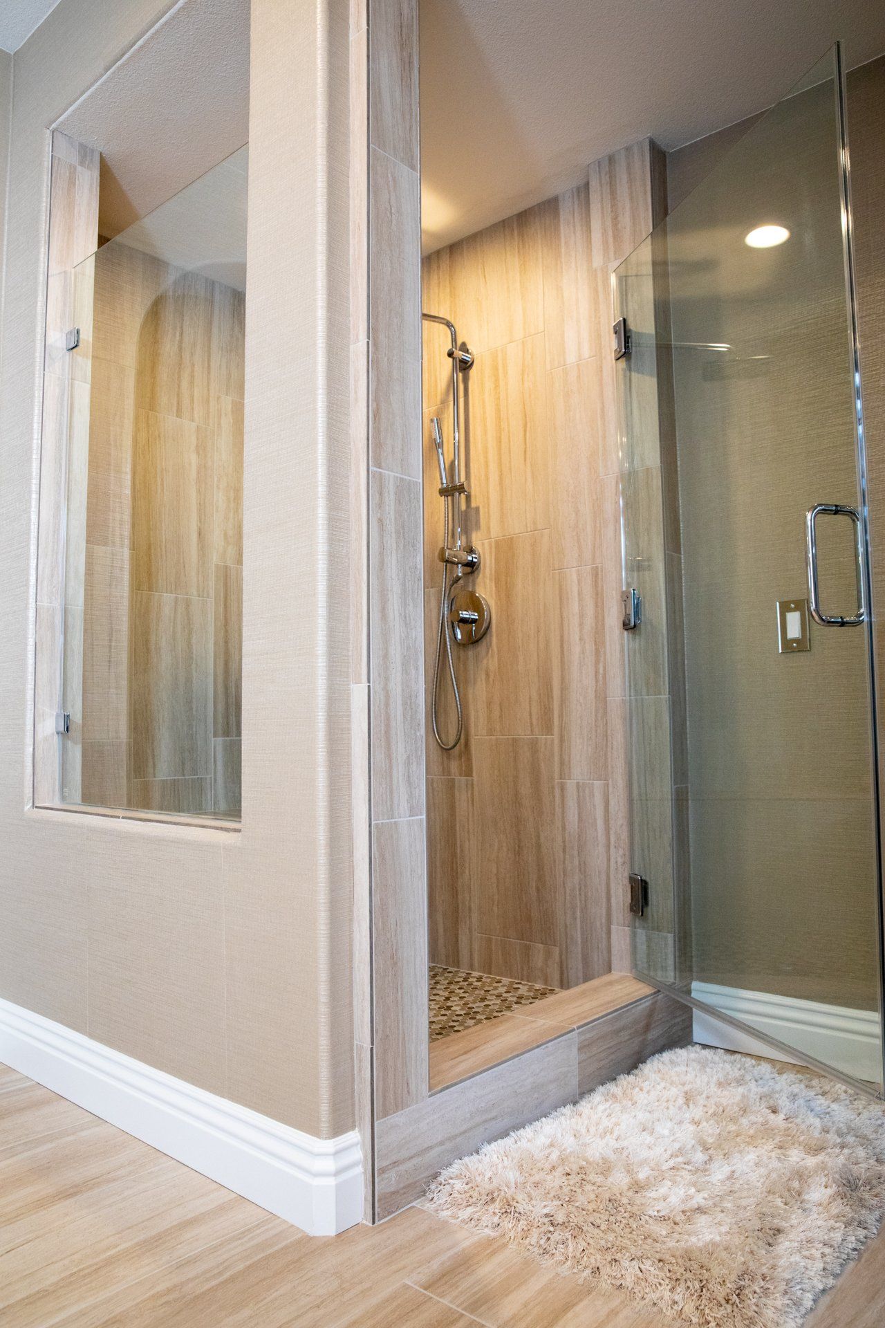 A bathroom with a walk in shower with a glass door