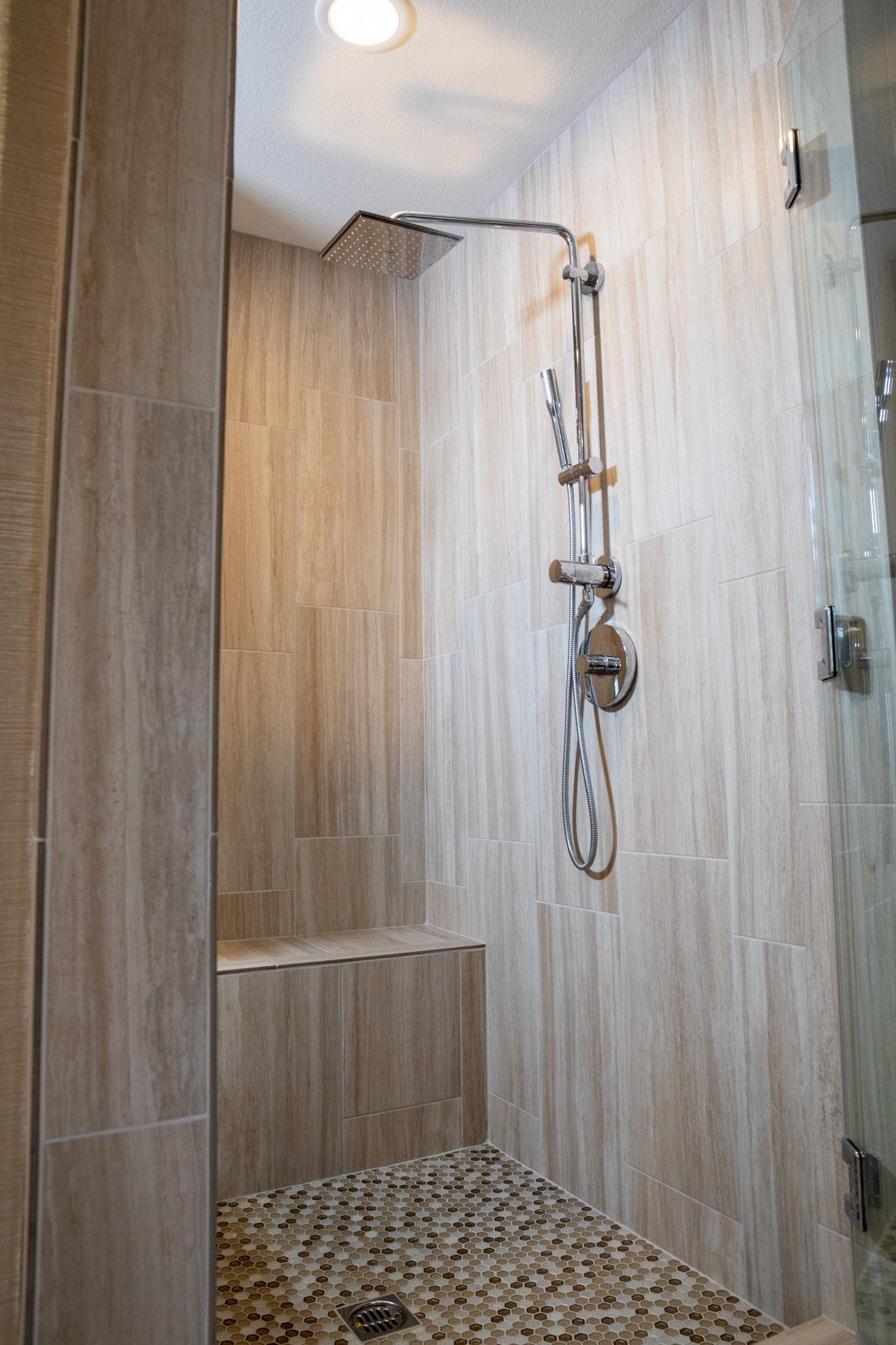 A shower with a bench and a shower head