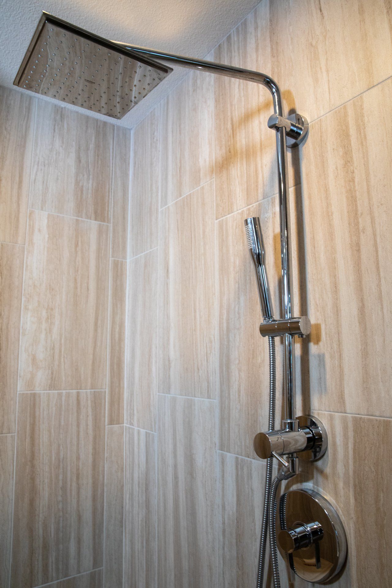 A shower head is hanging from the ceiling in a bathroom