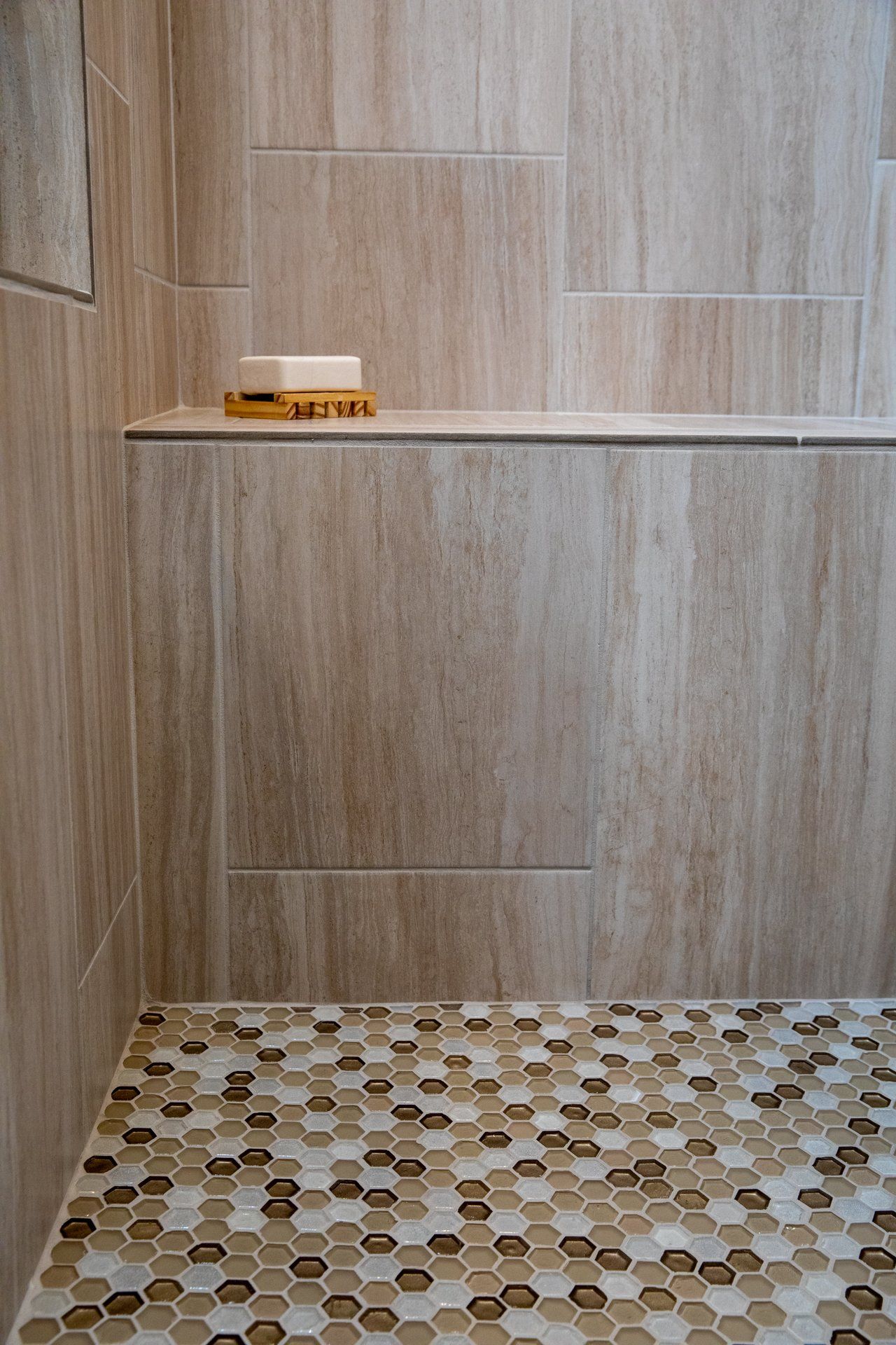 A soap dish sits on a shelf in a shower