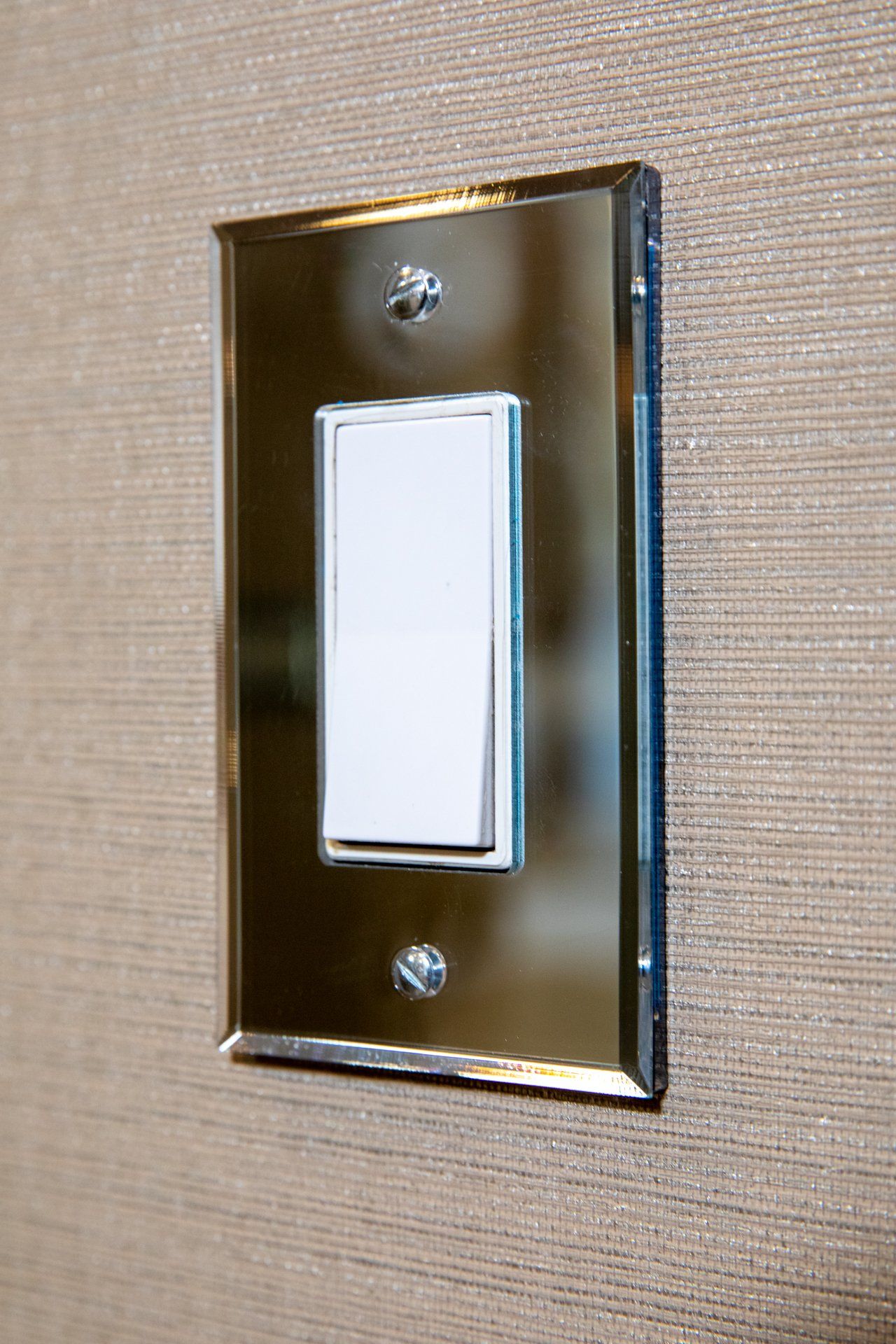 A light switch on a wall with a chrome frame
