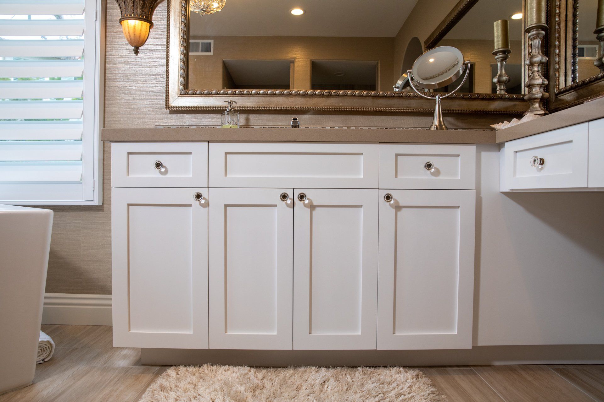 A bathroom with white cabinets and a large mirror