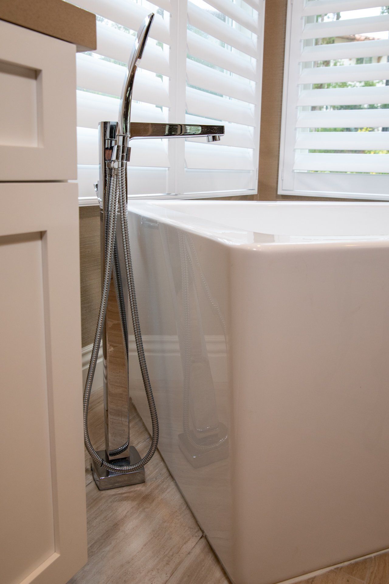 A bathtub in a bathroom with shutters on the window