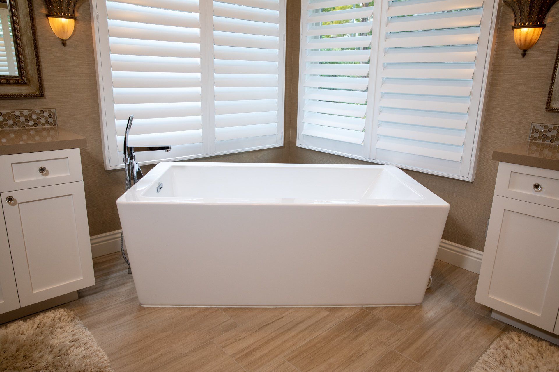 A bathtub in a bathroom with shutters on the windows