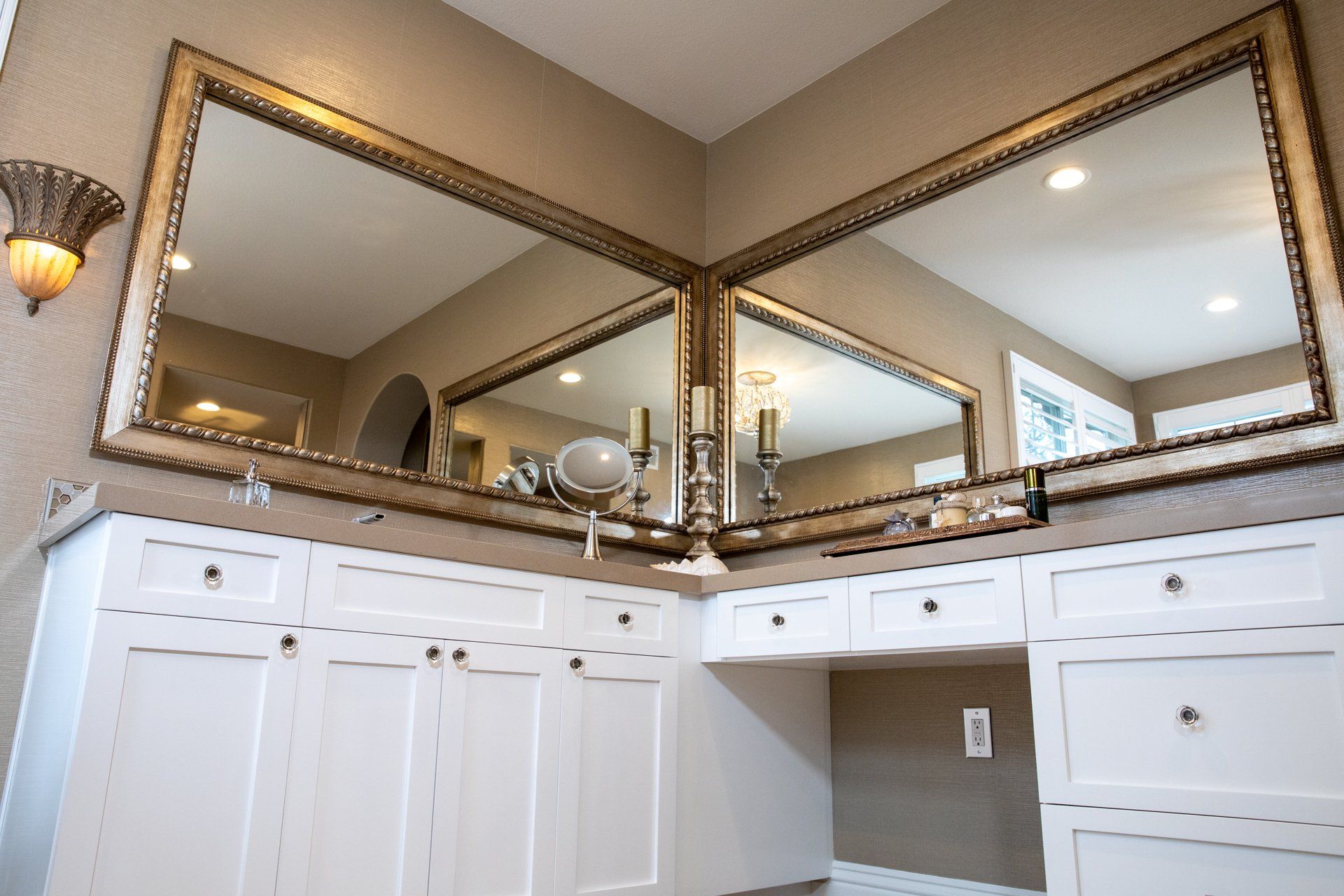 A bathroom with two large mirrors and white cabinets