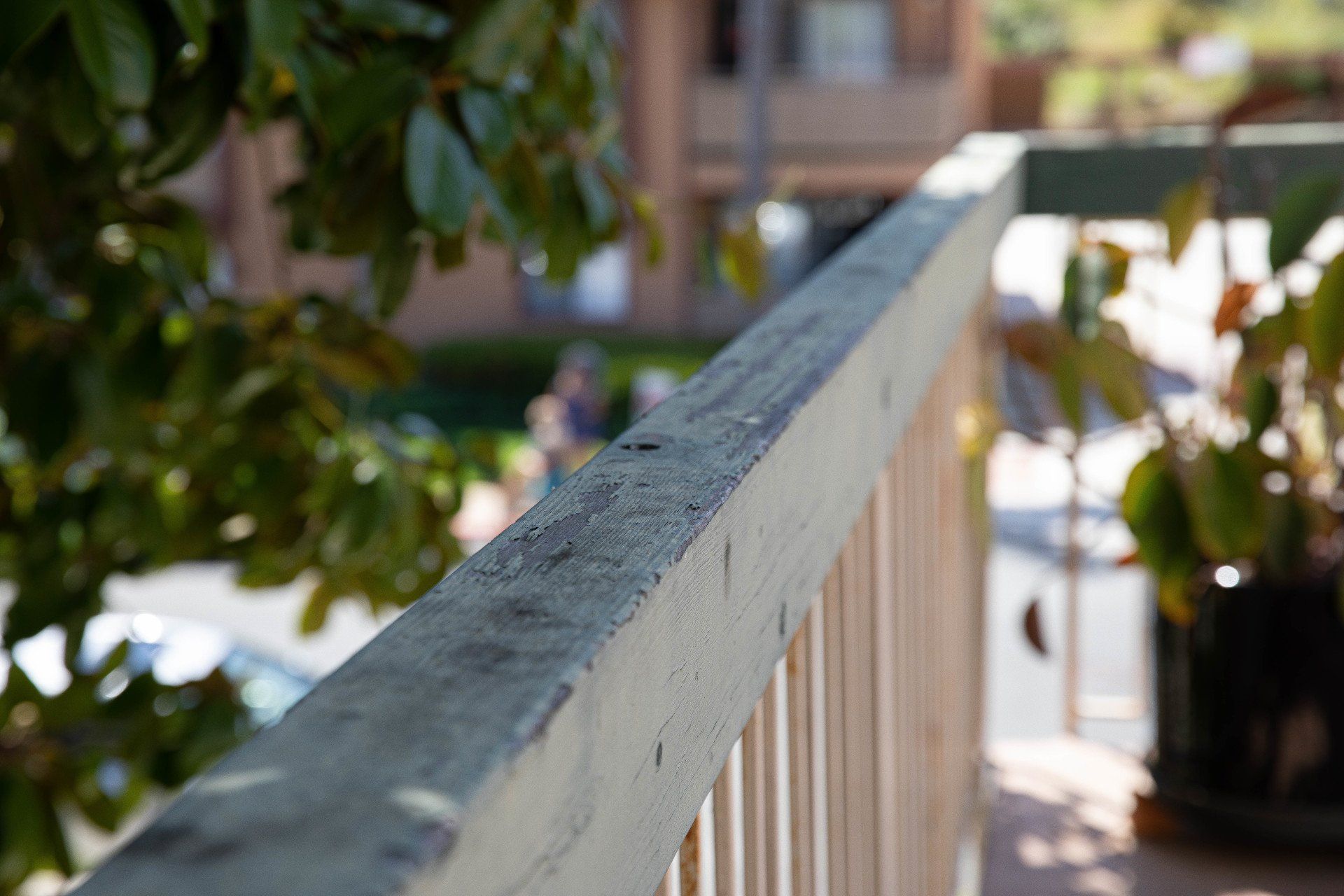A close up of a wooden railing with a tree in the background