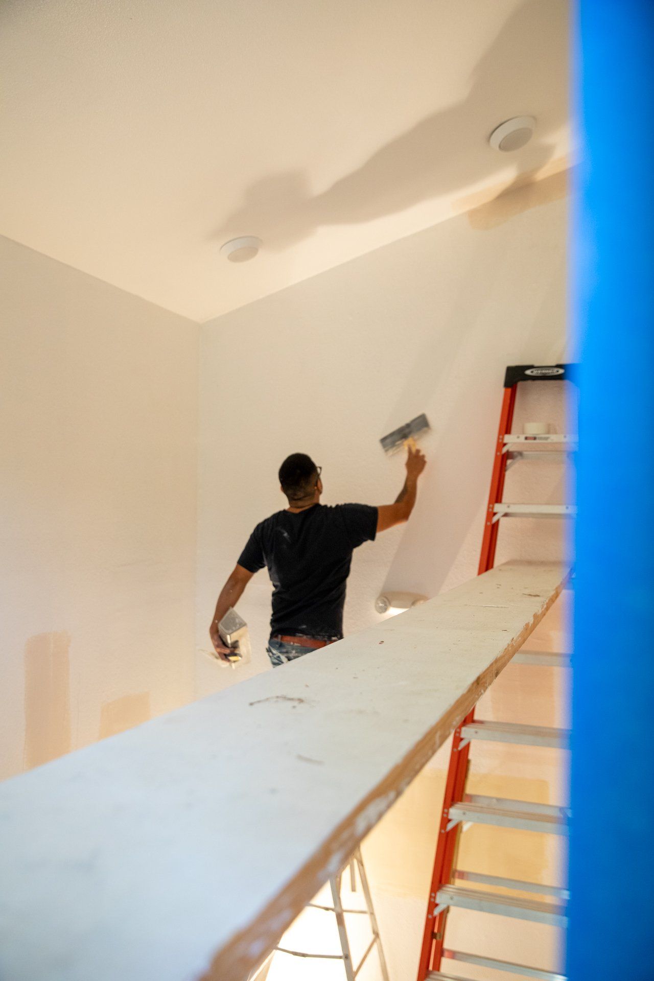 A man is standing on a ladder painting a wall
