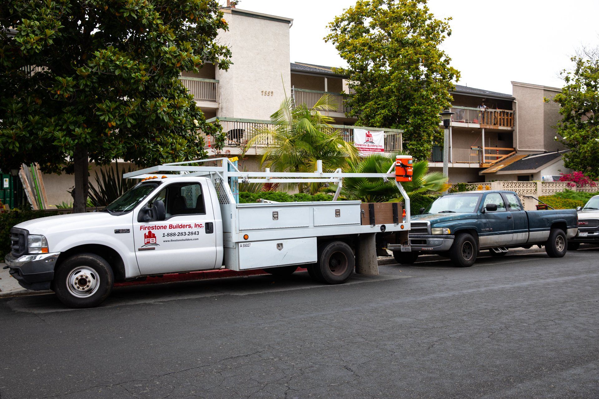 A white truck with a ladder on top is parked on the side of the road