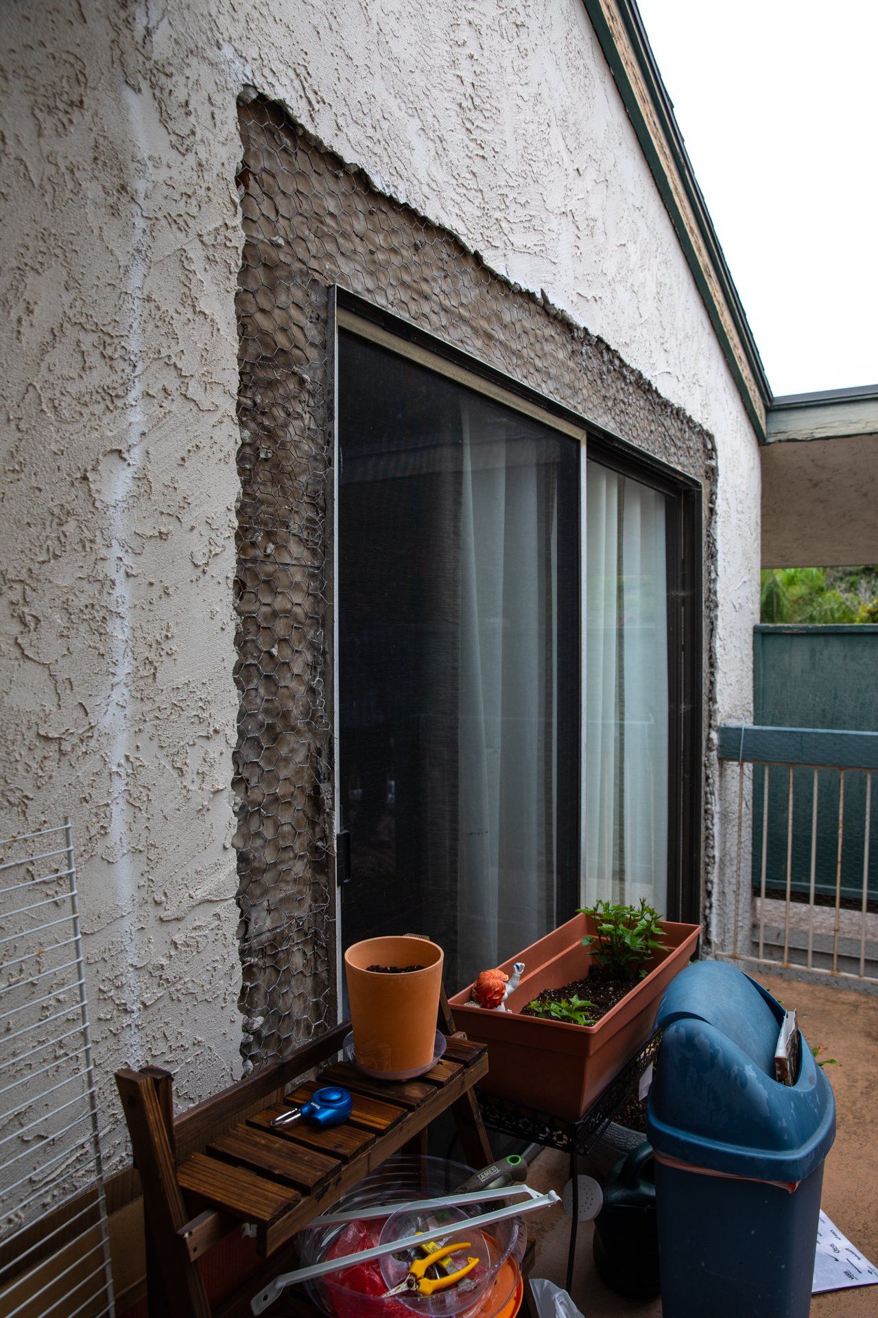 A balcony with a sliding glass door and potted plants