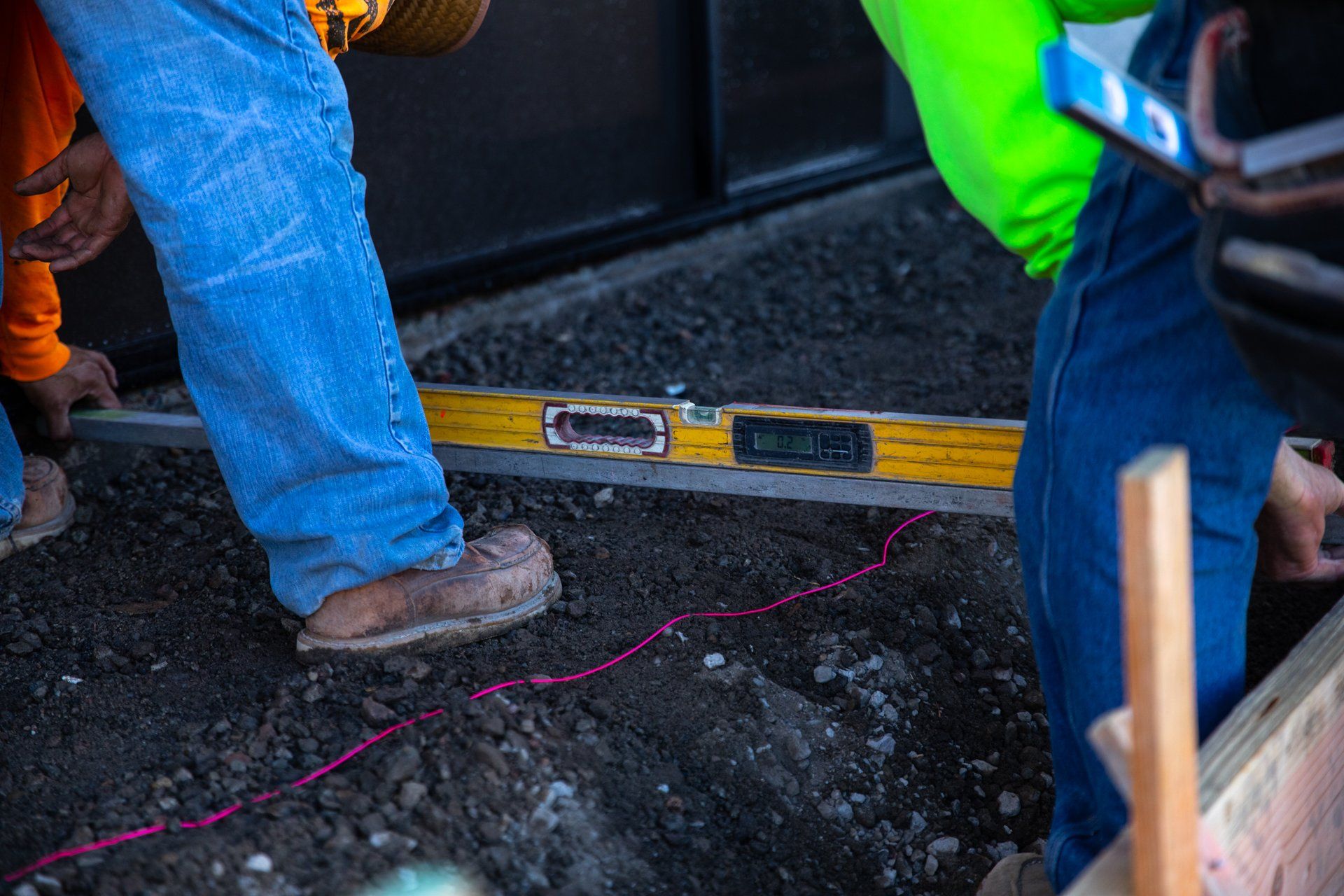 A construction worker is using a digital level on the ground