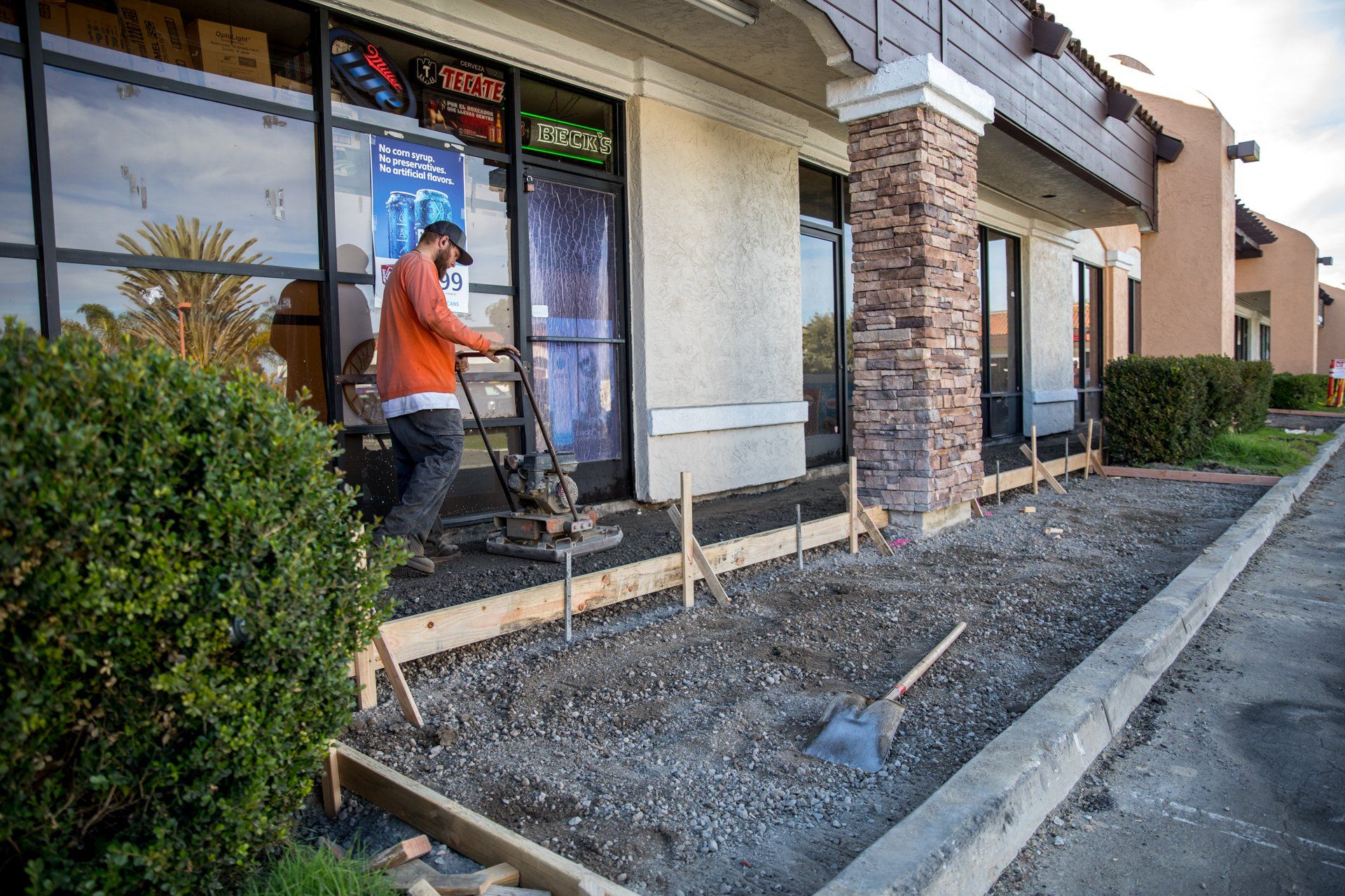 A man is working on a sidewalk in front of a pizza hut