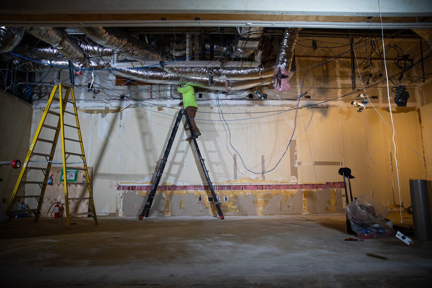 A man is standing on a ladder in an empty room.
