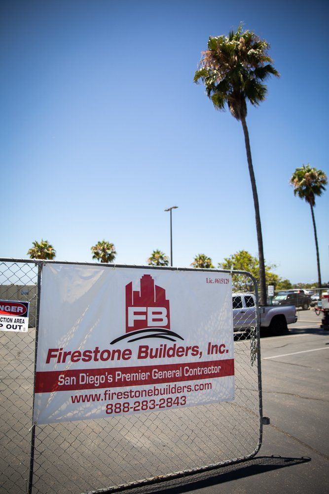 A sign for firestone builders inc. is on a chain link fence.
