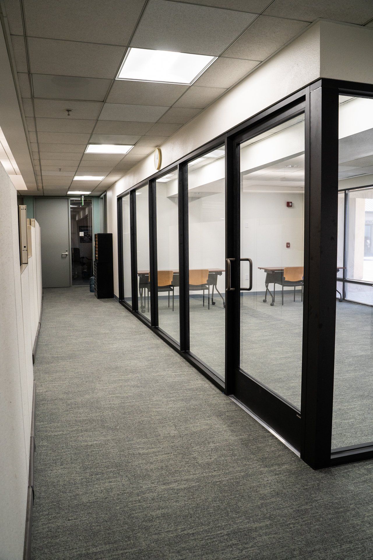 A long hallway with a lot of glass doors leading to a room.