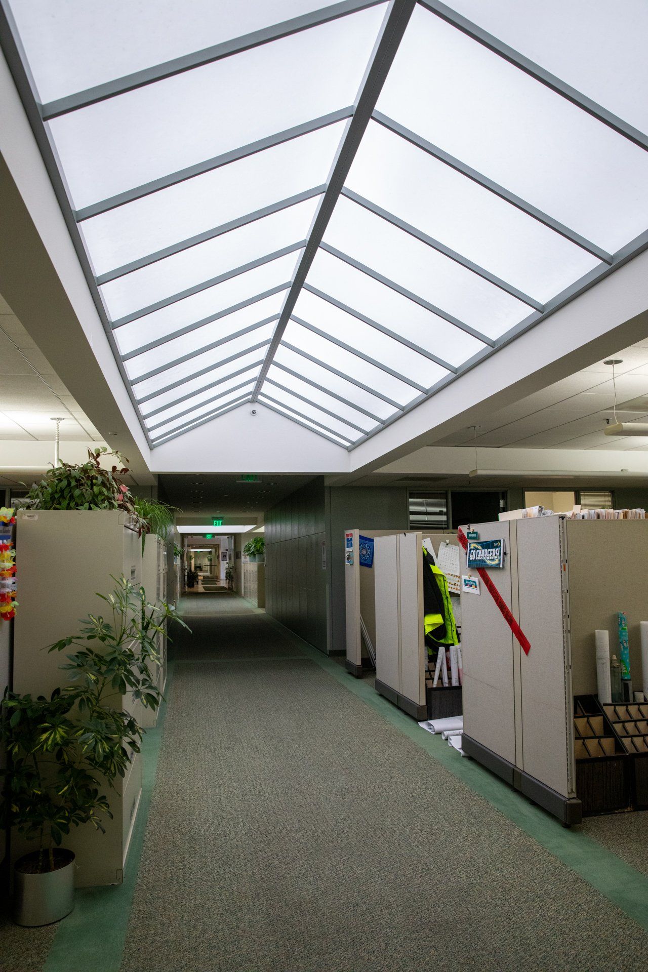 A hallway with cubicles and a skylight in the ceiling