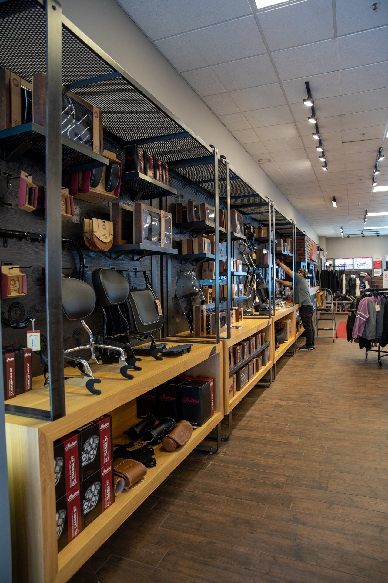 A man is standing in a store with a lot of shelves.