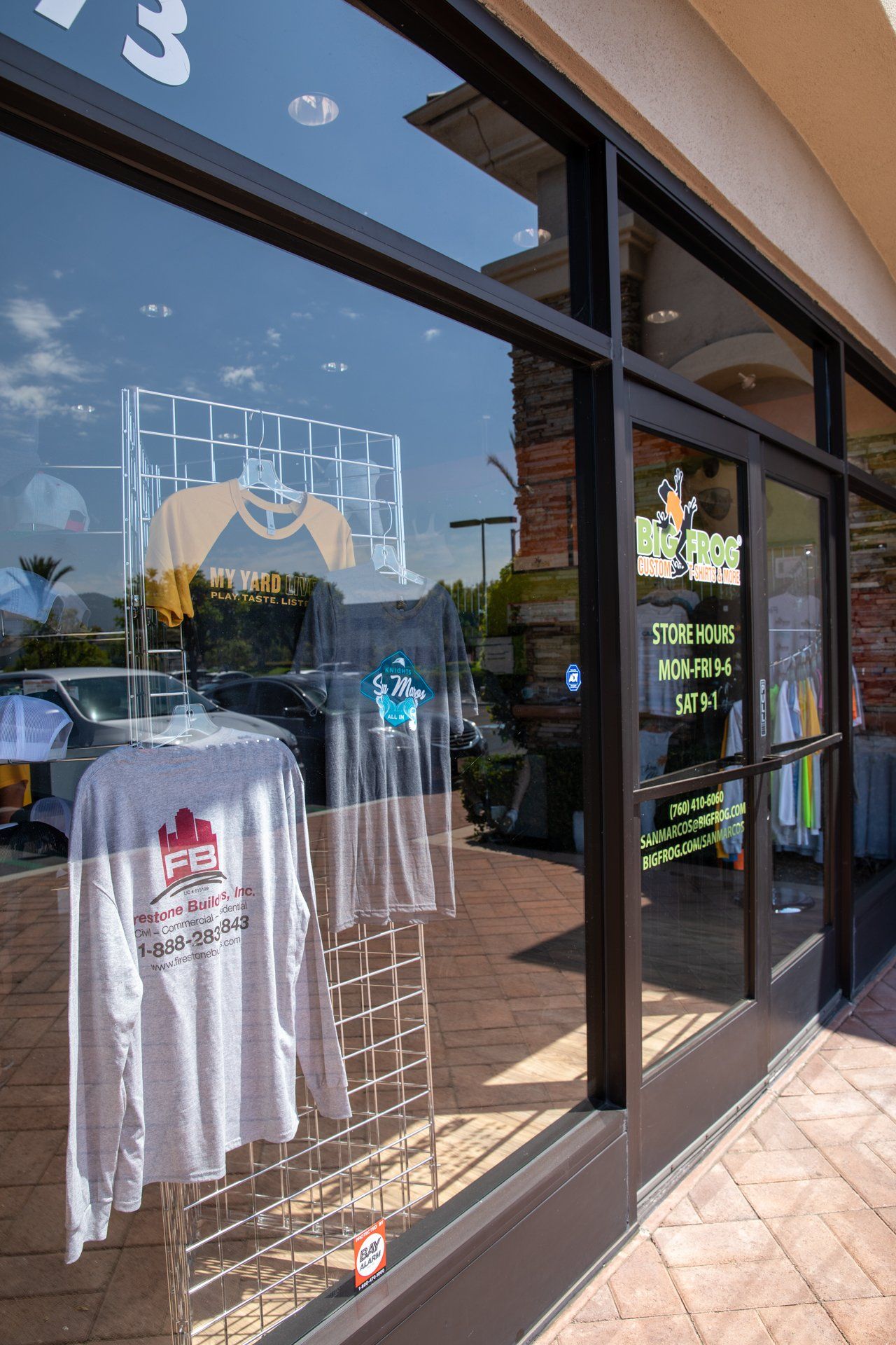 A store front with a lot of shirts hanging in the window.