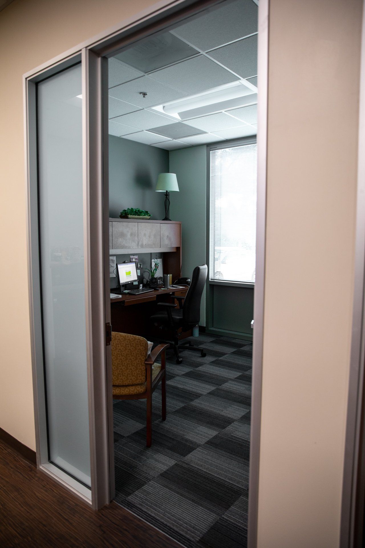 A room with a desk and chair in it and a sliding glass door.