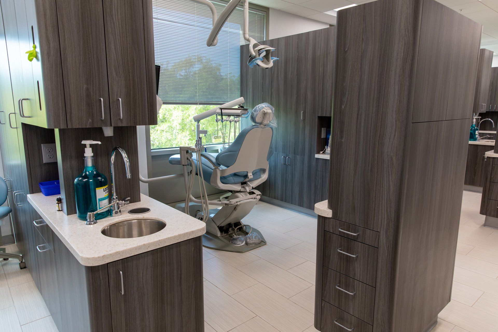 A dental office with a dental chair , sink and cabinets.