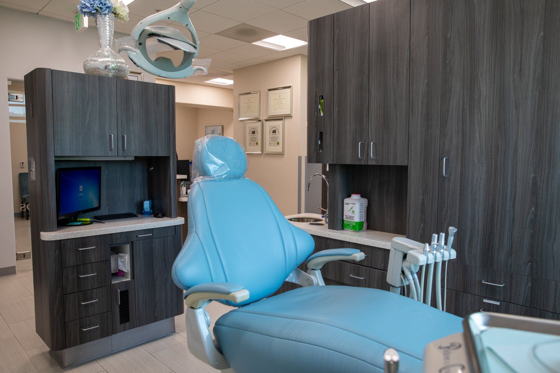A dental office with a blue dental chair and cabinets.