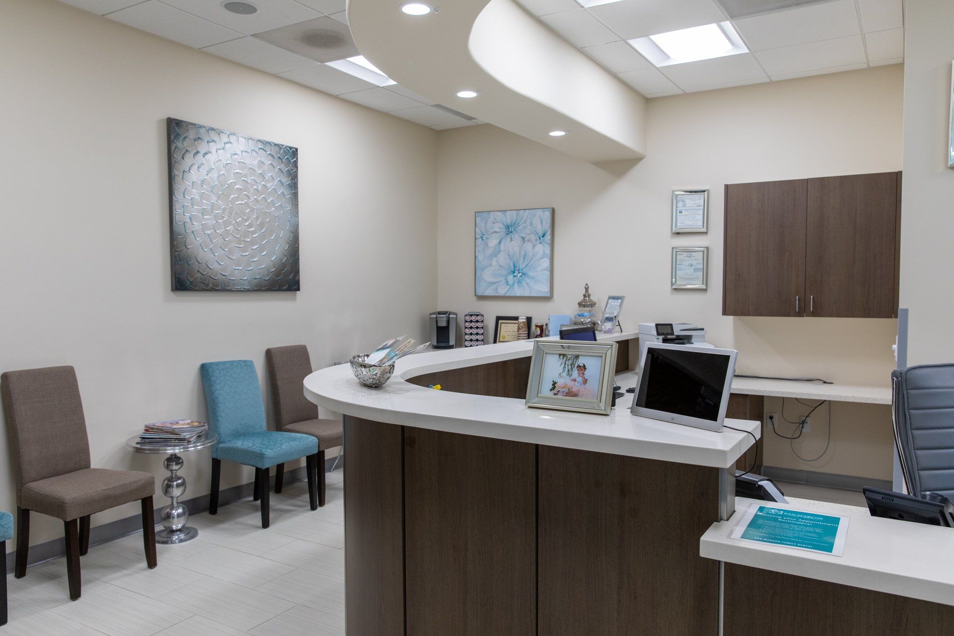A waiting room with a desk , chairs , and a laptop.