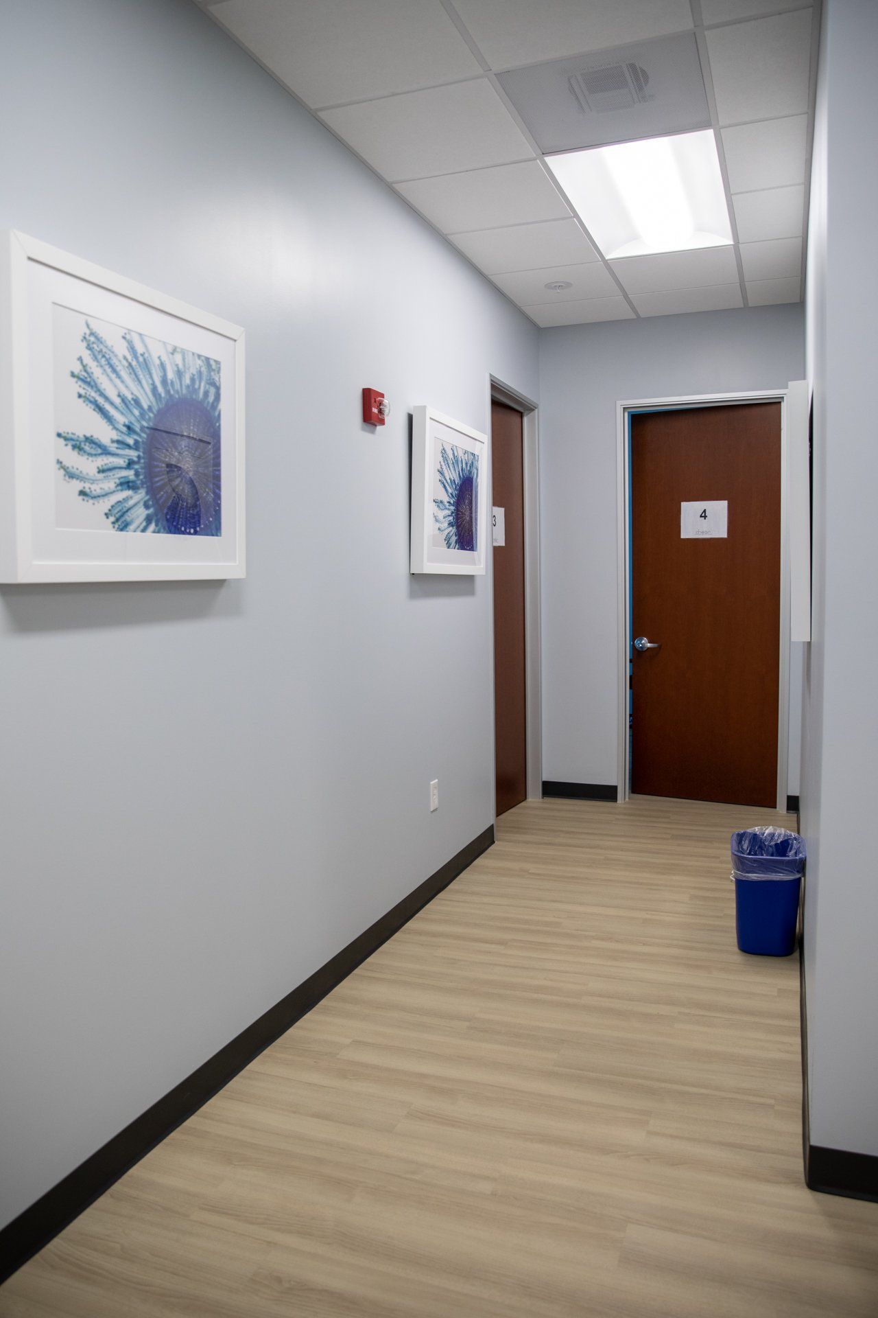 A long hallway with a blue trash can in the middle of it.