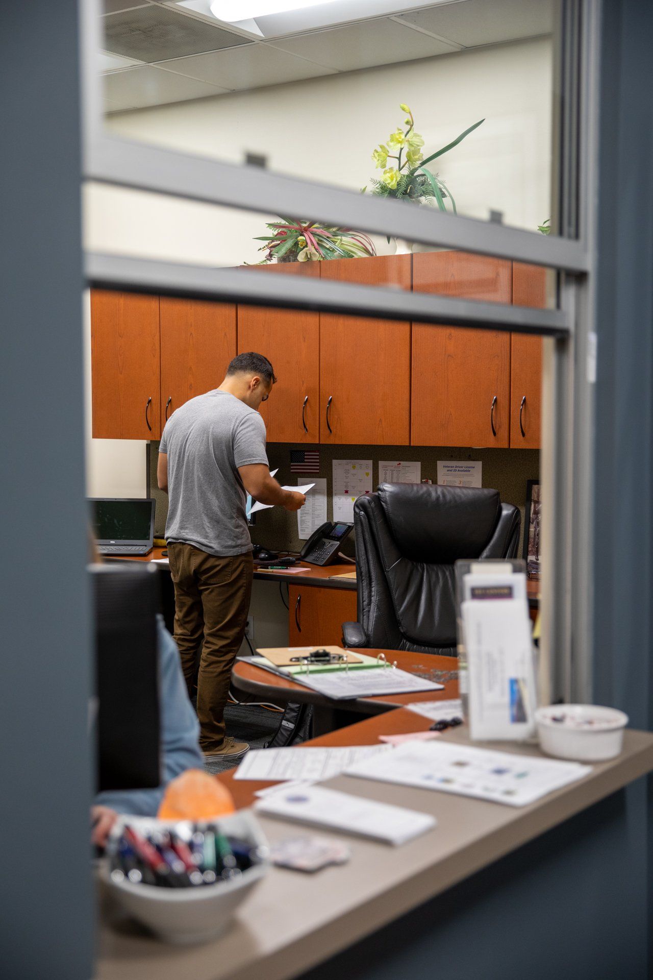 A man is standing in front of a desk in an office.
