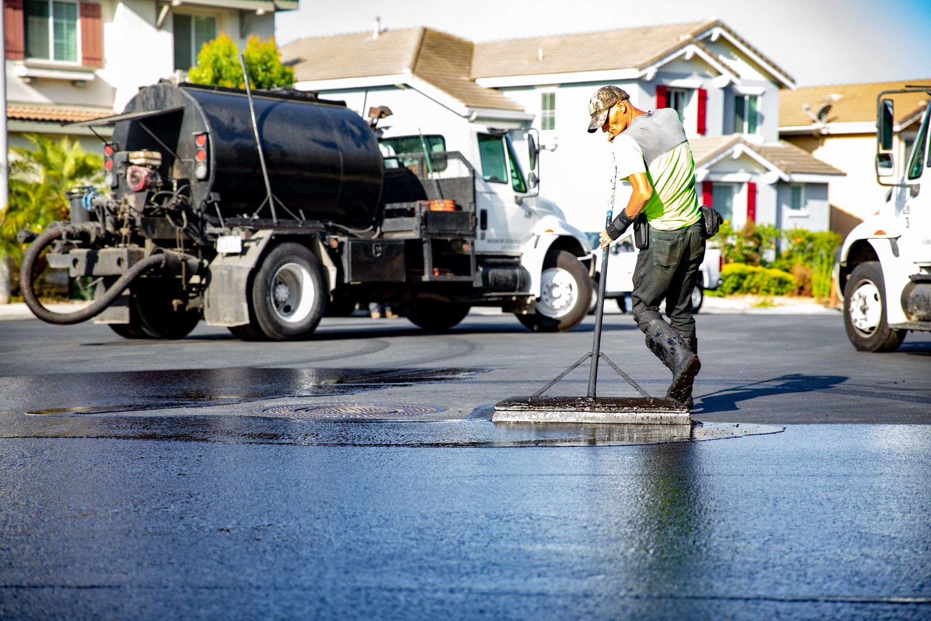 A man is spreading asphalt on a road next to a truck.