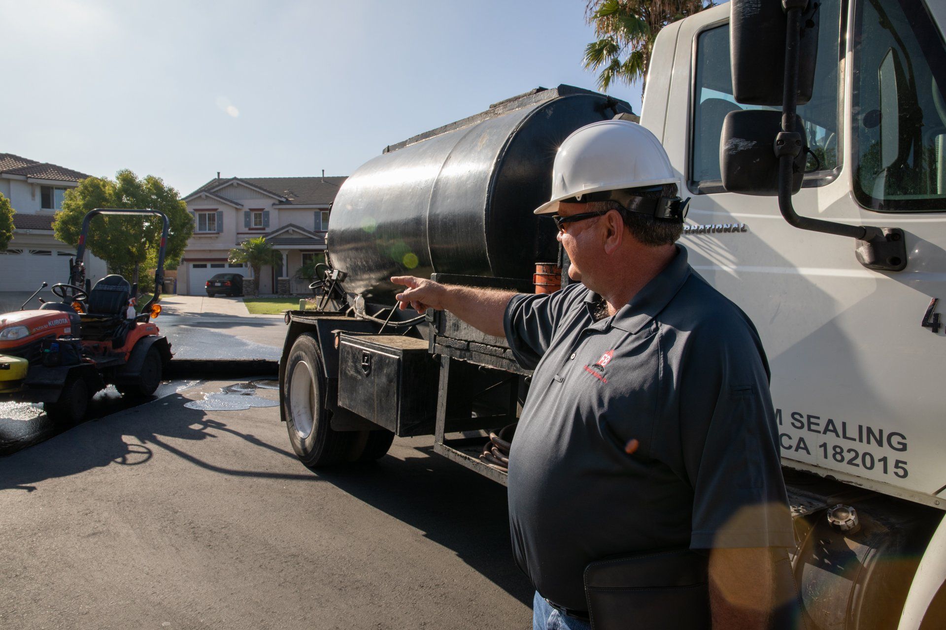A man wearing a hard hat is pointing at a truck that says ' sealing ' on it