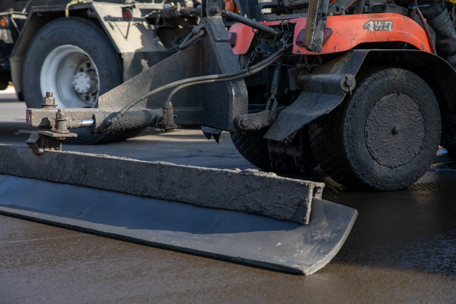 A tractor is spreading concrete on a road.