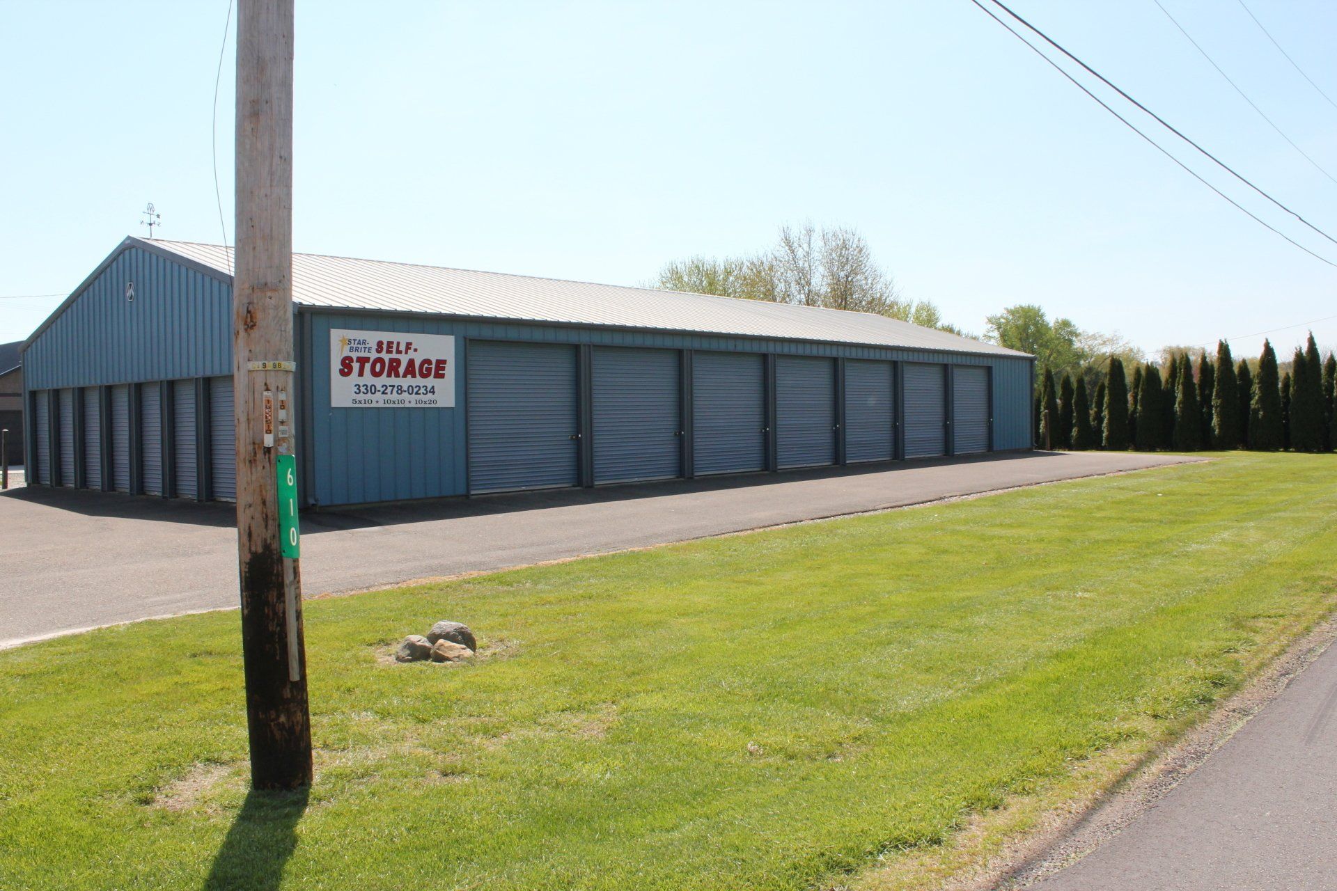 Storage units in a blue building with a sign and a green lawn.