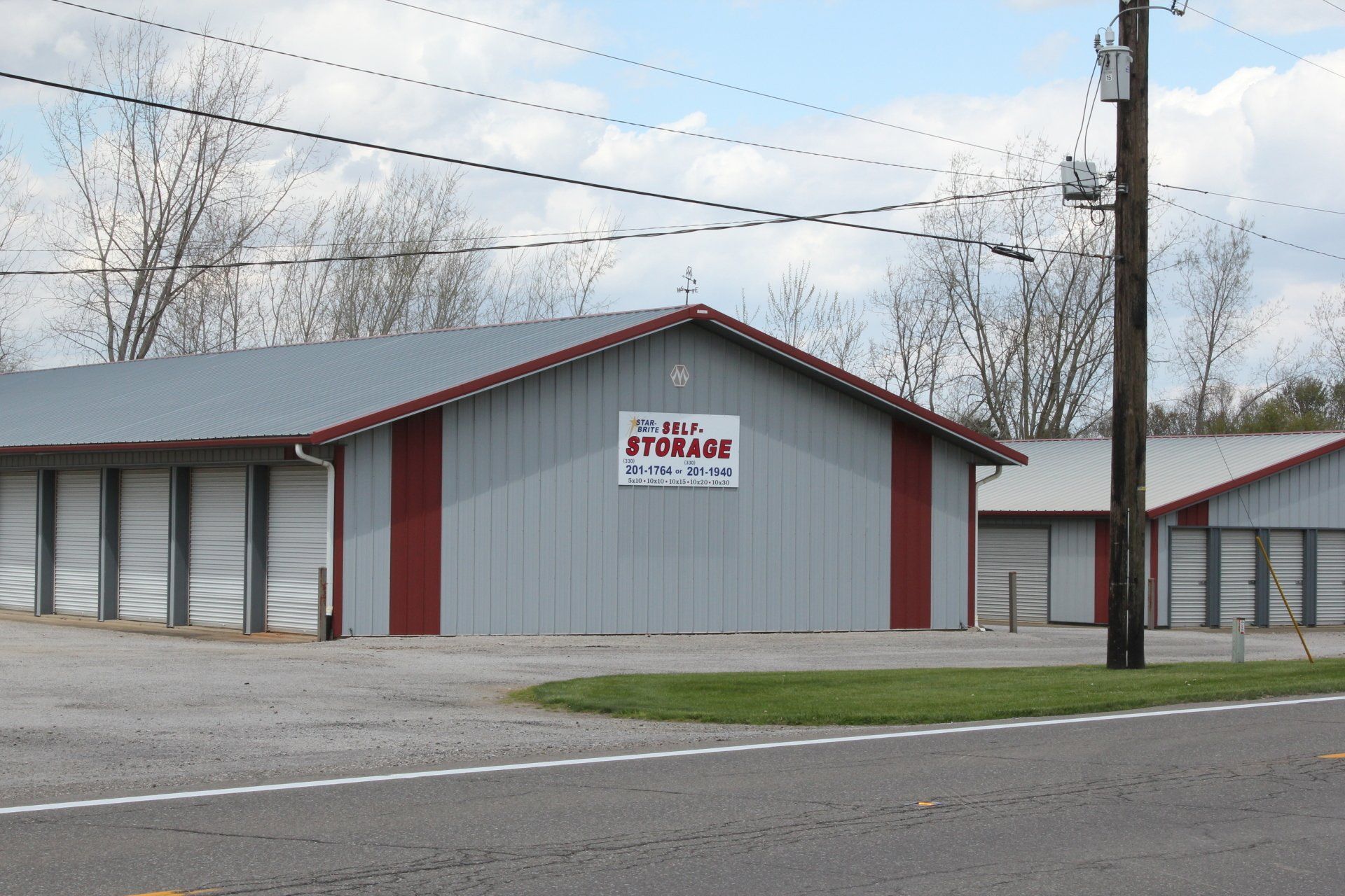 Storage units with gray and red siding. Sign: 