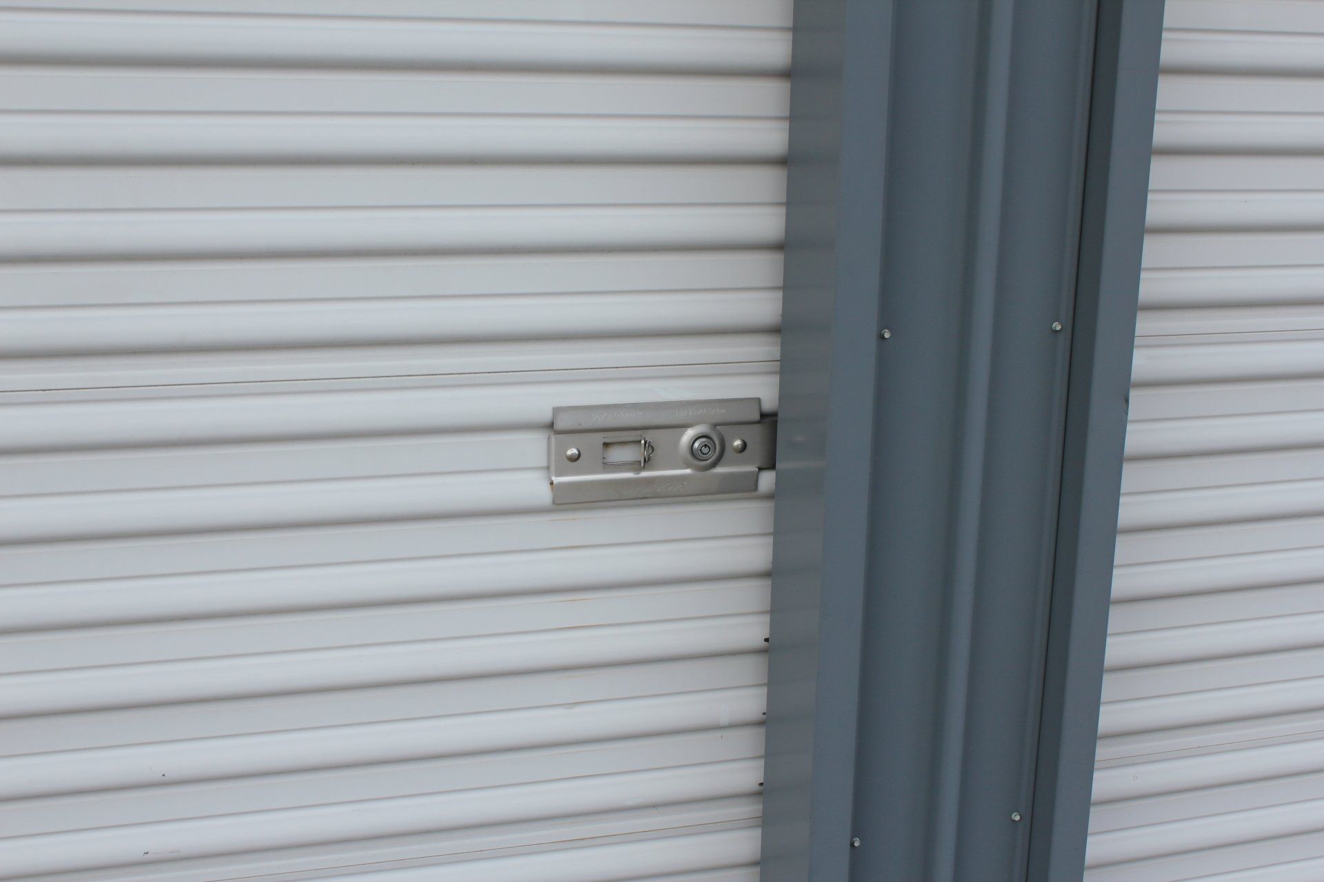 Close-up of a metal storage unit door with a lock plate and grey trim.
