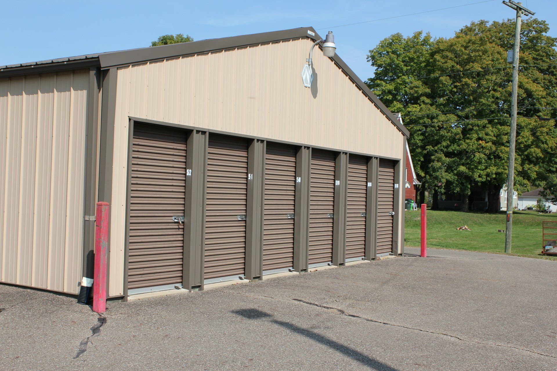 Storage units in a tan metal building with brown doors. A paved lot in front.