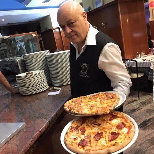 Il padrone con due pizze, una con mozzarella e l'altra, l’altra con peperoni