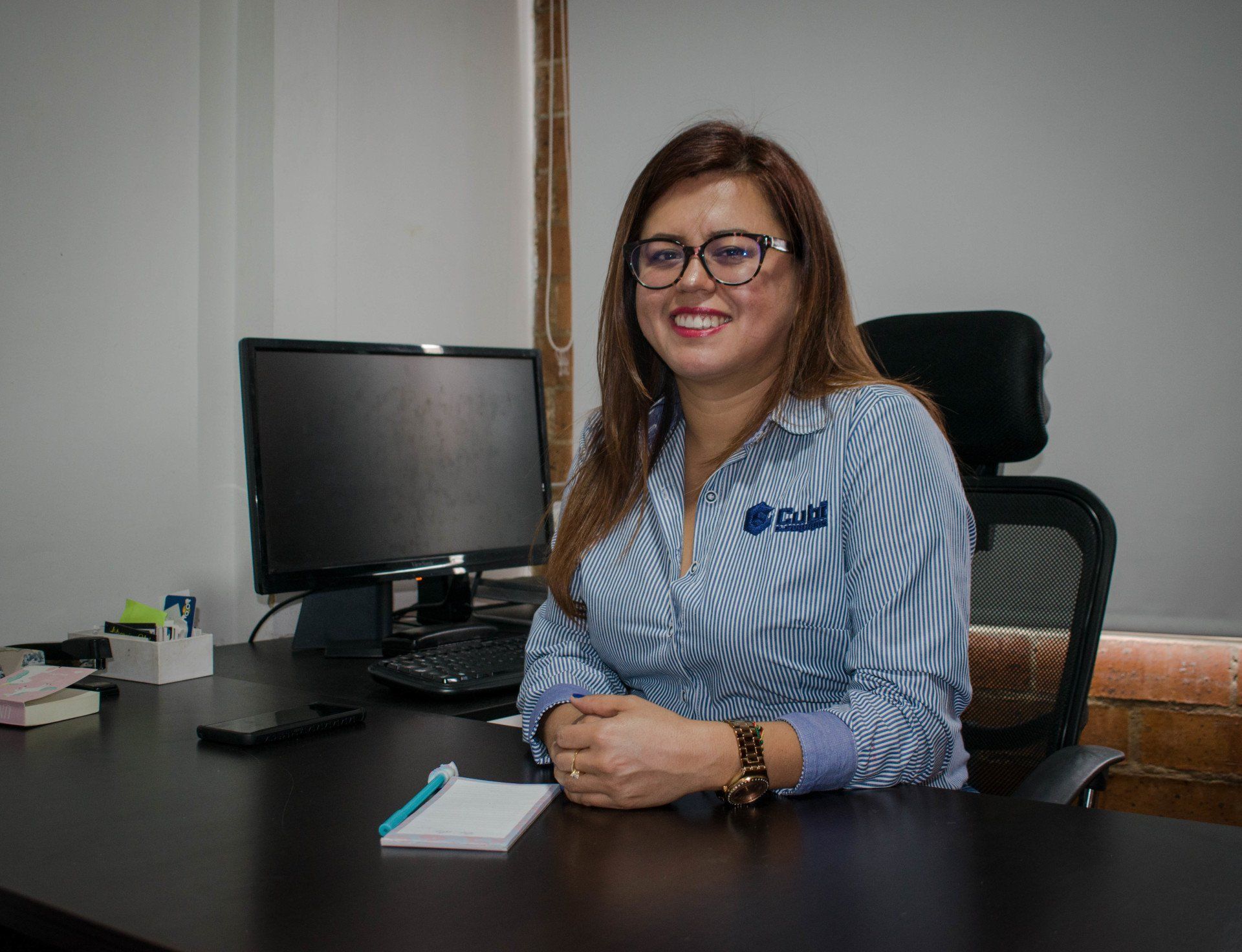 Una mujer está sentada en un escritorio frente a una computadora.