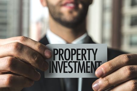 A man holds a Property Investment sign in his hands