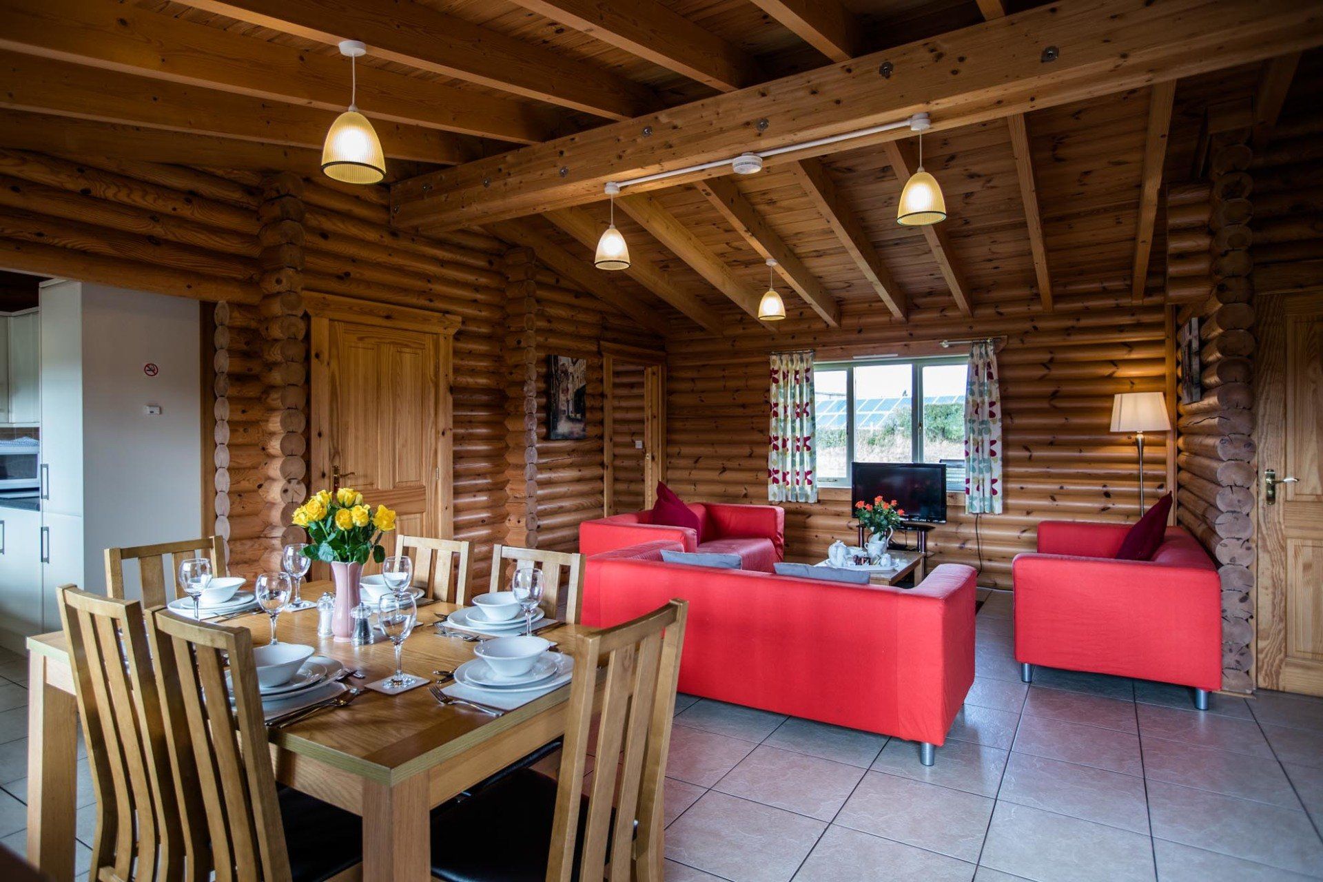 There is a dining table and chairs in the living room of a log cabin.
