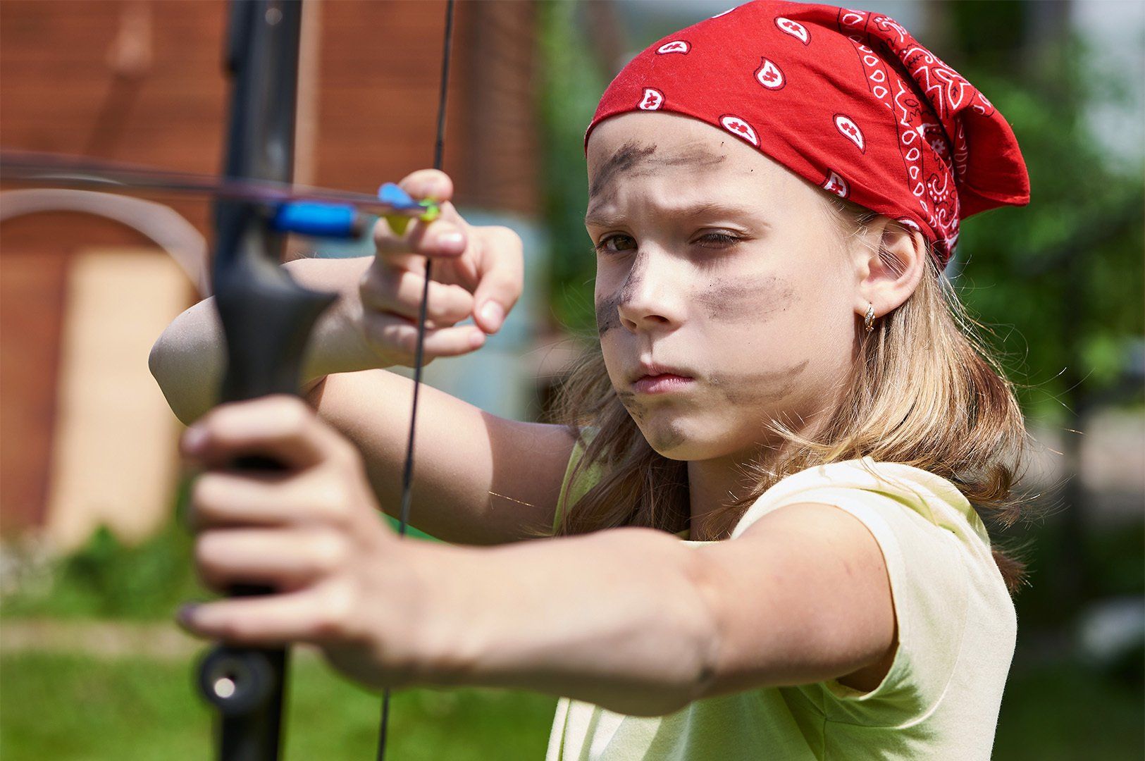 Girl archer with bow shooting to sport aim in sunny summer day