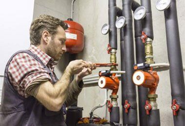 A man is working on a pipe with a wrench-The Trailer Factory In Port Macquarie, NSW