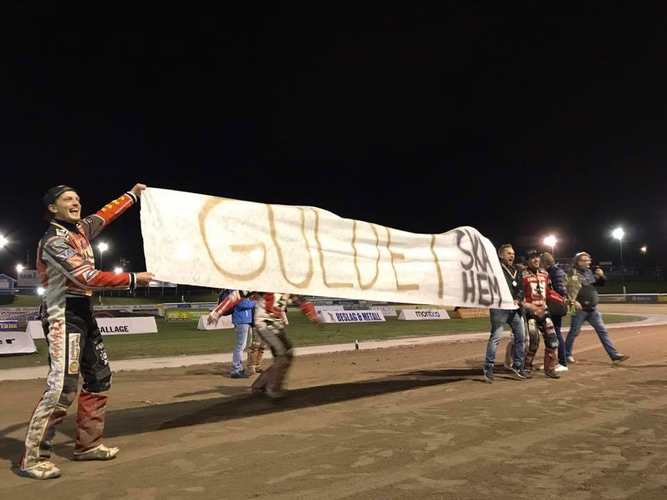 Speedway riders hold banner that reads 
