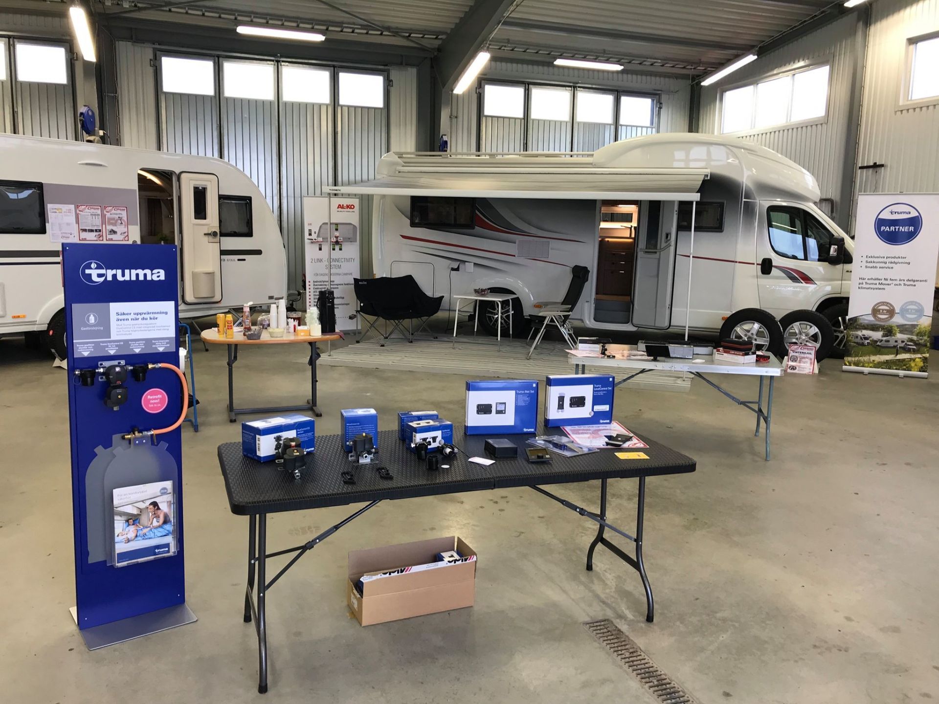 Camper vans and accessories displayed at an indoor event, showcasing camping equipment.