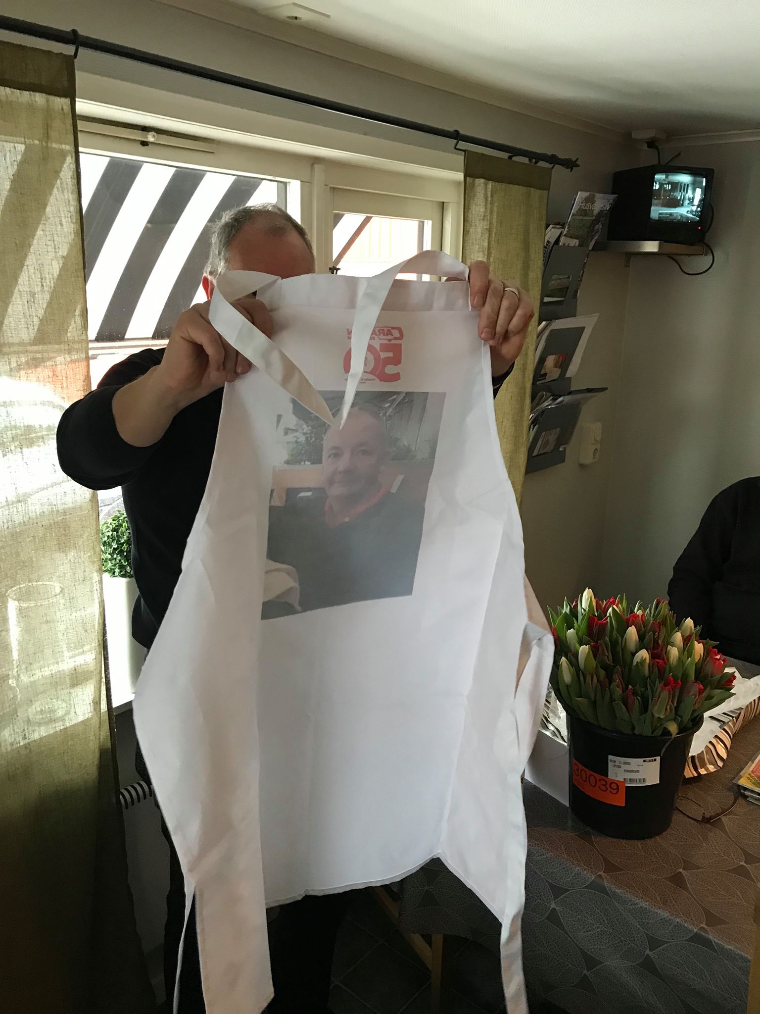 Man holding a white tote bag with a photo on it. Indoor setting.