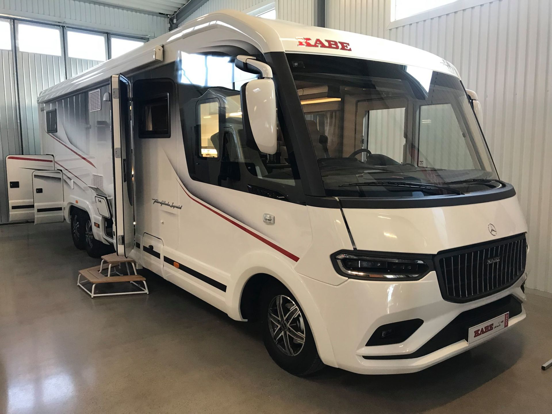 White recreational vehicle with open door; parked indoors.