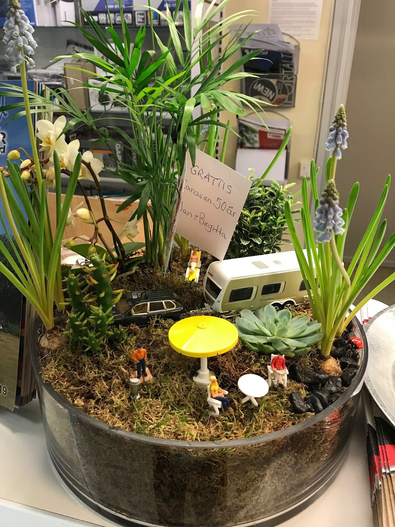 Miniature terrarium with camper, figures, and plants.