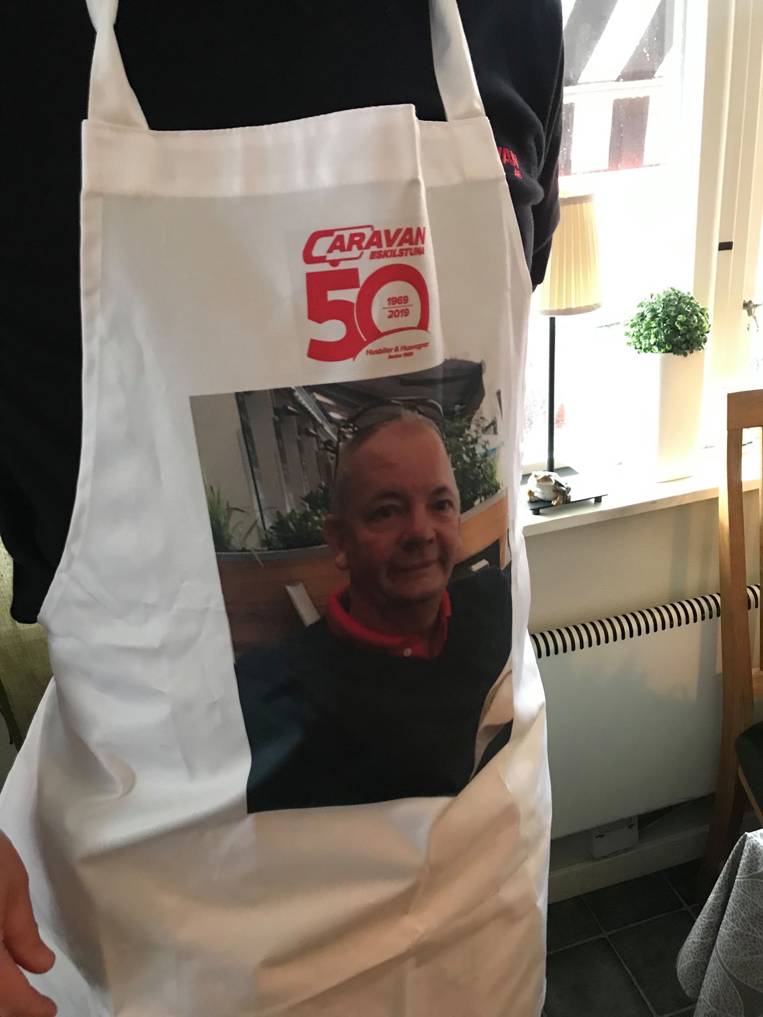 Person wearing white apron with a photo of a man and