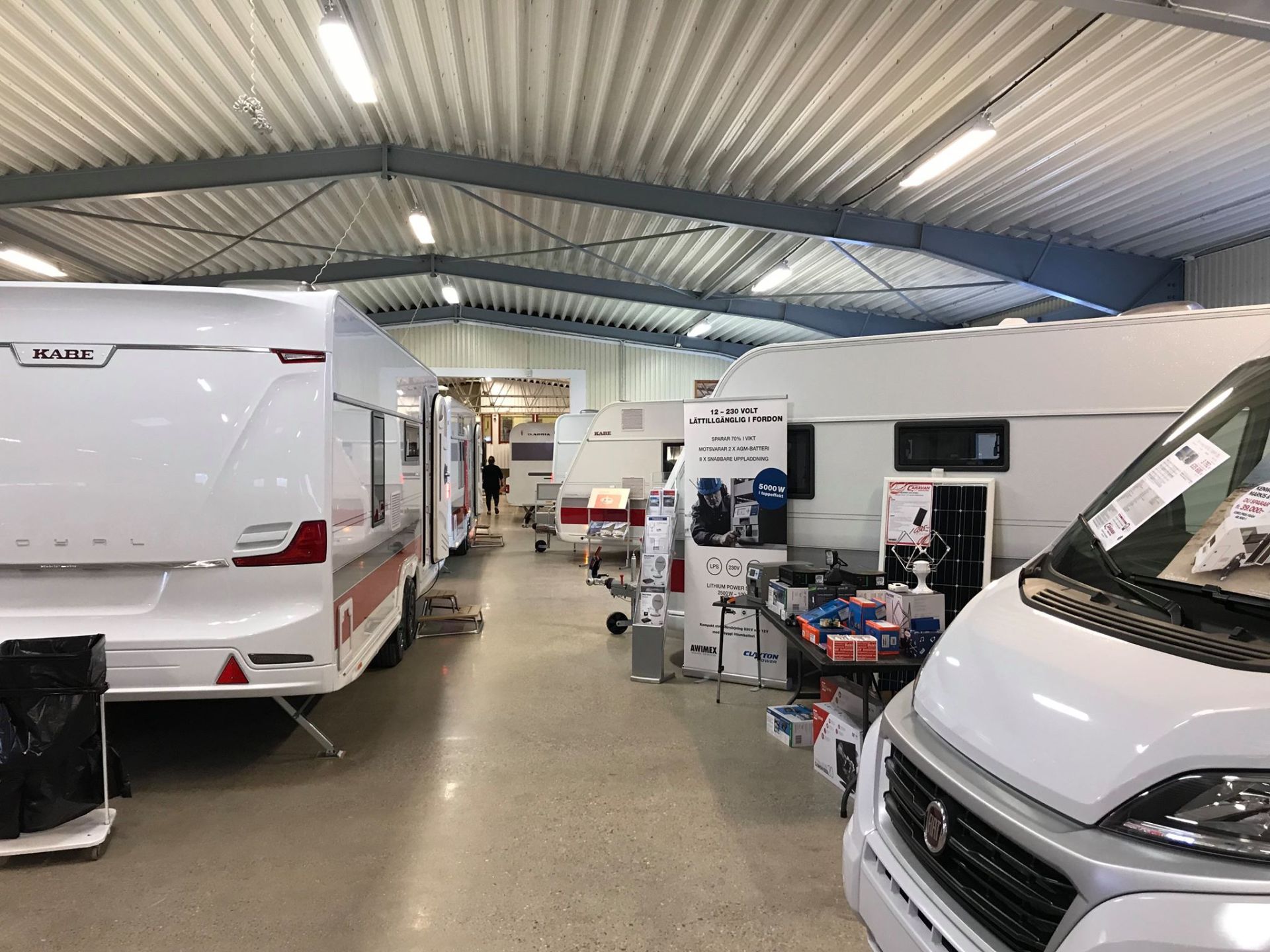 Inside a large warehouse showcasing RVs and camping supplies.